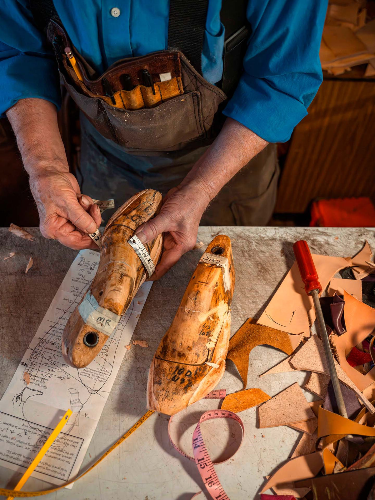 A bootmaker shaping a wooden last at the bench