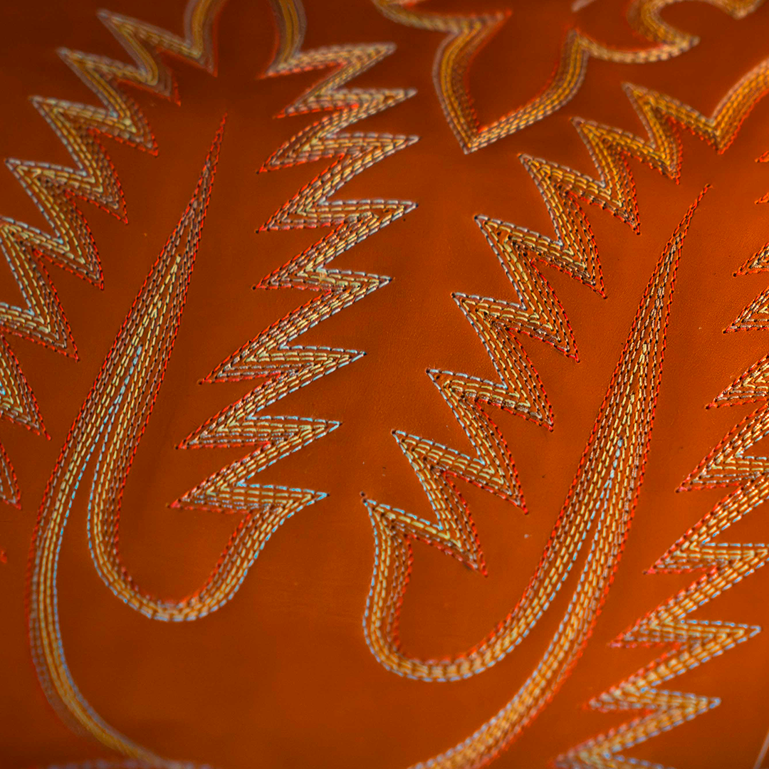 Multicolor stitching on an orange boot shaft