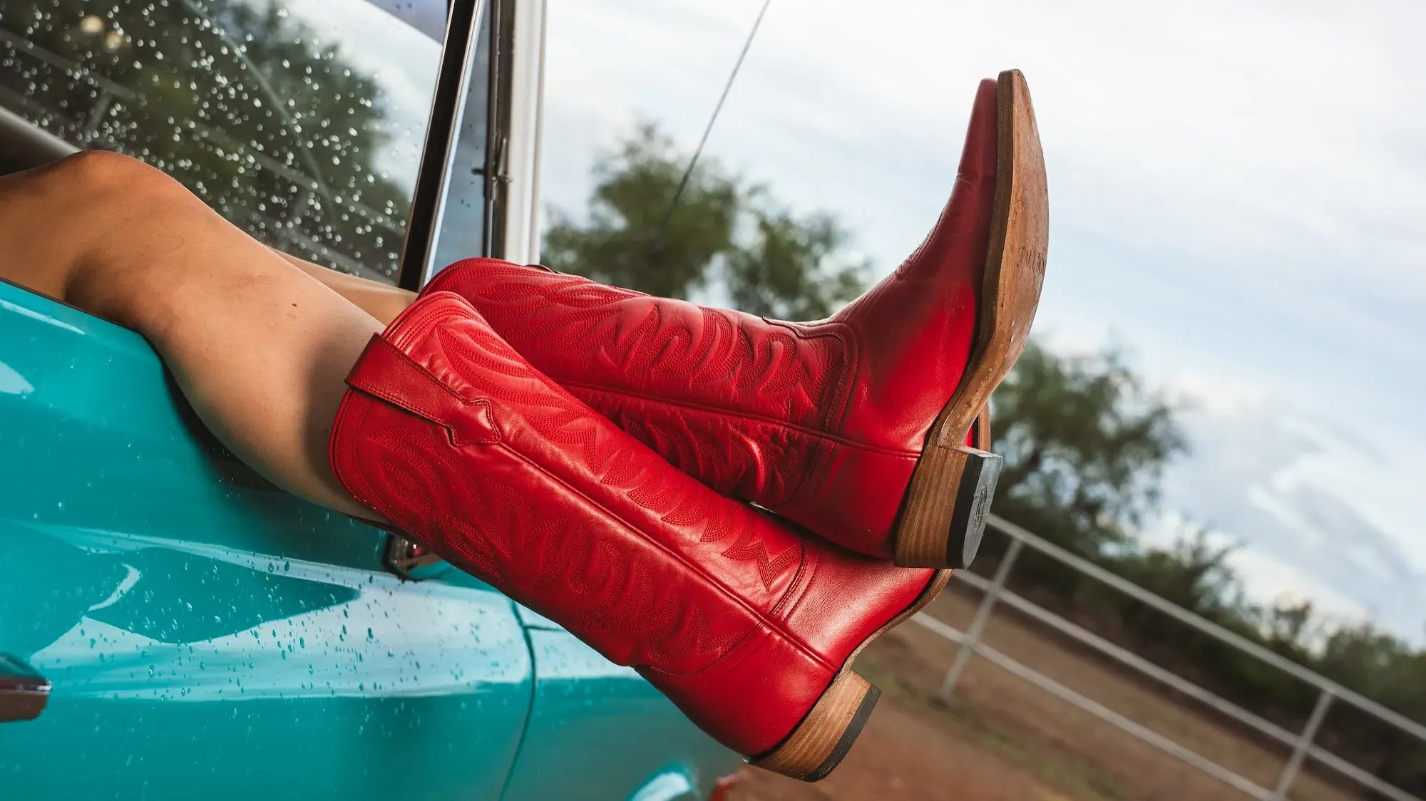 Red Paul Bond boots propped on the door of a turquoise truck